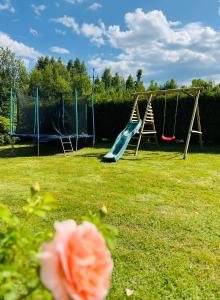 a playground with two swings and a slide at Polańczyk Dom, Apartamenty - Leśny Domek Polańczyk in Polańczyk