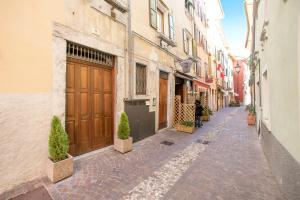 an empty alley with a building with brown doors at Nido sui Tetti di Riva del Garda - Happy Rentals in Riva del Garda