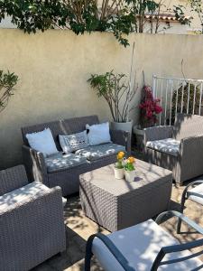 a patio with wicker chairs and couches and tables at Chambre privé avec piscine ,parking et cuisine prive in Marseille