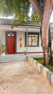 a house with a red door and a tree at Easyhomes mbezi beach in Dar es Salaam