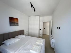 a white bedroom with a bed and a mirror at Driton`s Apartments in Shëngjin