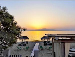 a sunset on a beach with chairs and umbrellas at Villa Laskarina in Skala Sotiros