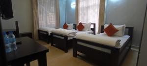 a hotel room with three beds and a table and a mirror at Nguchiro Palace Hotel in Moshi