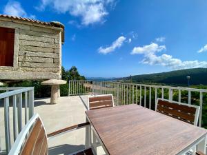 a patio with a wooden table and chairs on a balcony at Casa das Laixas in Laxe