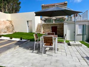 a patio with a table and an umbrella at Casa das Laixas in Laxe