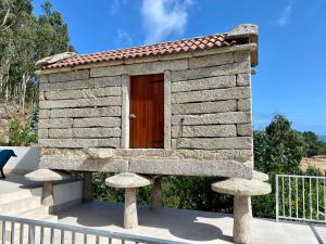 a small stone dog house with a wooden door at Casa das Laixas in Laxe