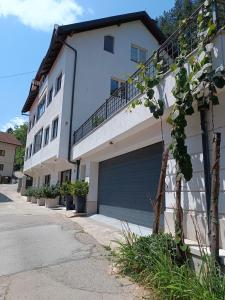 a white building with a garage door next to a street at Apartment Stari Pazar 3 in Konjic