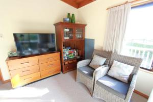 Pohara Sands - Family Beach House في Pohara: غرفة معيشة مع تلفزيون وكرسي ومركز ترفيهي +19 صورة