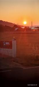 a sunset in a field with the sun setting at Pensión atlantico in Muxia