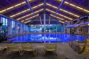 a pool in a building with chairs and a table at RIKKA KHUST thermal resort in Khust