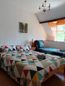 a bedroom with a colorful bed and a couch at Maison de caractère - L'évasion forestière in Baguer-Pican