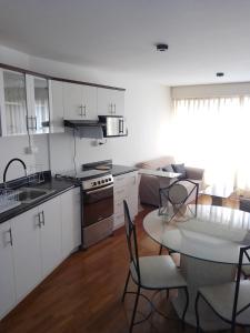 eine Küche mit weißen Schränken und einem Tisch mit Stühlen in der Unterkunft Miraflores, Lima, apartamento 2 dormitorios in Lima
