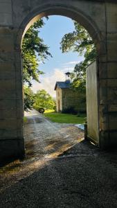 an archway leading to a building with a church in the background at L'Écrin du Marquis 