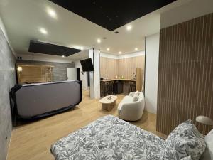 a living room with a bed and a large screen tv at Élégance spa suite in Thiers