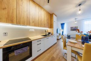 a kitchen with wooden cabinets and a dining table at Onyx Oasis Residence- City Centre, Free Parking by StayNest in Rzeszów