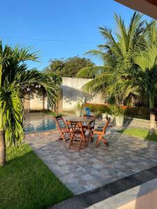 a patio with a table and chairs and palm trees at Recanto do Lima in Camocim +36 photos