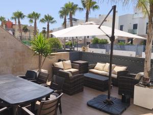 a patio with a table and chairs and an umbrella at CHALET ADOSADO DULCINEA Alcossebre in Alcossebre