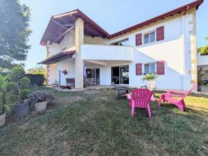 a house with two pink chairs in the yard at Appartement familial 118 m2 proche Bayonne in Hasparren