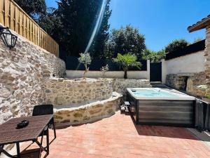 a patio with a hot tub and a stone wall at La Maisonnette de Mouragues in Foix