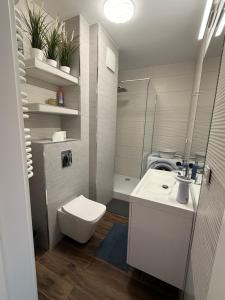 biała łazienka z toaletą i umywalką w obiekcie MIĘDZYZDROJE,BALTICUS PROMENADA GWIAZD 14, Apartament z odrębnym salonem i sypialnią z Widokiem na morze w mieście Międzyzdroje