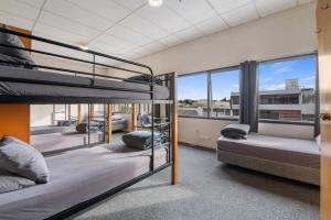 a group of bunk beds in a room with windows at Rock Solid Backpackers Rotorua in Rotorua