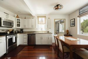 een keuken met witte kasten en een houten tafel bij Blissful Bay Cabin in Big Bear Lake