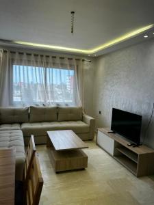 a living room with a couch and a television at Nouvel Appartement Parc Mohammedia in Mohammedia