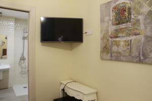 baño con TV de pantalla plana en la pared en Hostal Flor De Lis- Lojo, en Conil de la Frontera