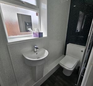 ein Badezimmer mit Waschbecken, Toilette und Spiegel in der Unterkunft 4 Bed Family & Work Ready Home in Ponders End