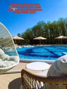 a large swimming pool with two chairs and umbrellas at Aze - Green Business in Bucharest