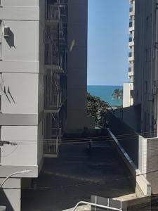 an alley between two buildings with the ocean in the background at castanheiras perto de tudo,com cadeiras e guarda sol in Guarapari