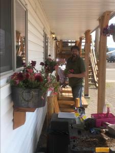 a man standing next to a house with flowers at Yellowstone Holiday Motel in West Yellowstone