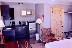 a room with a bed and a chair and a kitchen at Yellowstone Holiday Motel in West Yellowstone