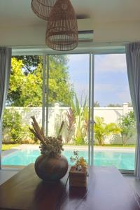 a dining room with a large window and a table with plants at One villa kep in Phumĭ Dâmnăk Châng'aeur