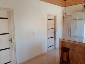 MelgaçoKitnet do Oberdan的一间厨房,厨房拥有白色的墙壁、一个柜台和凳子