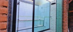 a glass shower in a bathroom with a brick wall at Ficar Bem Lumiar in Nova Friburgo +8 photos