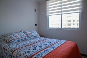 una camera con letto con trapunta e finestra di Departamento 2H1B La Serena Condominio Distrito Verde a La Serena