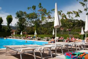 a pool with lounge chairs and people sitting around it at Il Frantoio Camping in San Bartolomeo al Mare