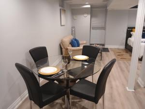 a dining room with a glass table and black chairs at Furnished calm basement studio apartment in Mississauga