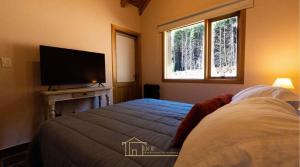 une chambre avec un lit et une télévision à écran plat dans l'établissement Cabaña en Chapelco Golf San Martin de los Andes 2 Habitaciones, à San Martín de los Andes