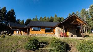 une maison en rondins avec un toit noir dans l'établissement Cabaña en Chapelco Golf San Martin de los Andes 2 Habitaciones, à San Martín de los Andes