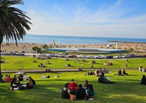 un groupe de personnes assises dans l'herbe près d'une plage dans l'établissement MDQ viva!, à Mar del Plata