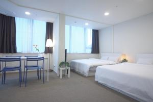 a hotel room with two beds and a table and chairs at The Comfort Triny Hotel in Yongin