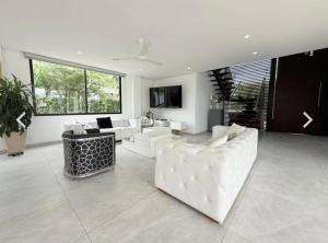 a living room with white furniture and a large window at Casa con piscina y BBQ en Lagos del Peñón Girardot in Girardot