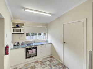 a kitchen with a stove and a microwave at Apsley Cottage Hosted by Halls Gap Accommodation in Halls Gap +4 photos
