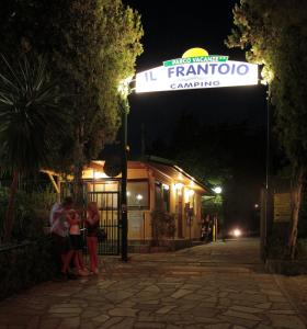 un grupo de personas de pie bajo un cartel por la noche en Il Frantoio Camping, en San Bartolomeo al Mare