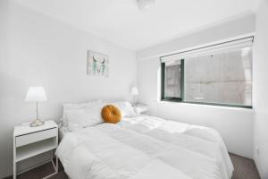 a white bedroom with a large bed and a window at Stylish Braddon Retreat 2Bedroom Free Parking & Pool in Braddon +12 photos
