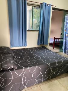 a bed in a room with blue curtains and a window at Casa em Bonito in Bonito