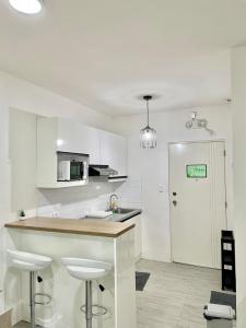 a kitchen with white cabinets and a counter with stools at Nuvali - Free use of Massage Chair-Pool Access-Hot Shower in Calamba +14 photos