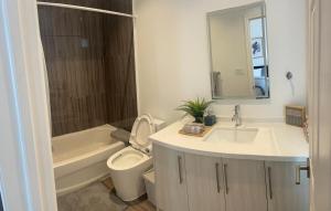 een badkamer met een wastafel, een toilet en een ligbad bij Two Adjacent 4 Bedroom Townhouse Units in the Fallsview District Walk to the Falls in Niagara Falls +39 foto's